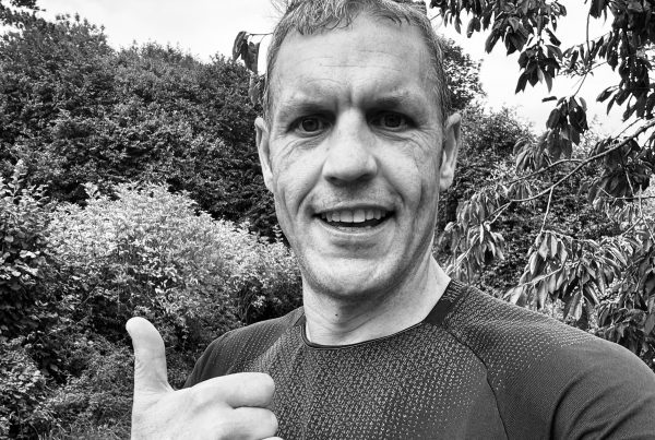 Person giving thumbs up outdoors.